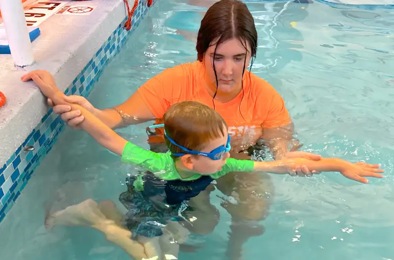 Special Needs Banner Girl kid learning to swim with women coach at swimming pool